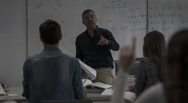 Profesor de matemáticas señalando a un estudiante durante una clase.